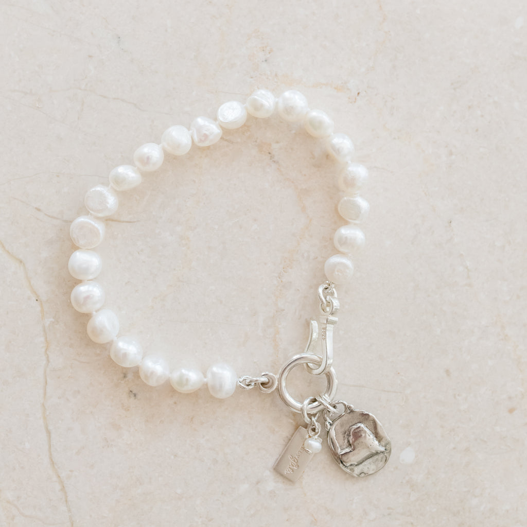 Eloise Pearl Bracelet by Pearly Girls, a single nugget freshwater pearl bracelet adorned with an artisan heart charm. This piece elegantly showcases the unique beauty of a solitary nugget pearl, complemented by a handcrafted heart charm, symbolizing love and artistry.