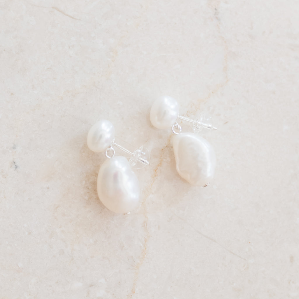 Baroque and Button Pearl Earrings by Pearly Girls merge timeless style with modern flair. These earrings showcase the unique texture of baroque pearls paired with smooth button pearls, offering an elegant contrast that brings a contemporary twist to classic pearl jewelry.