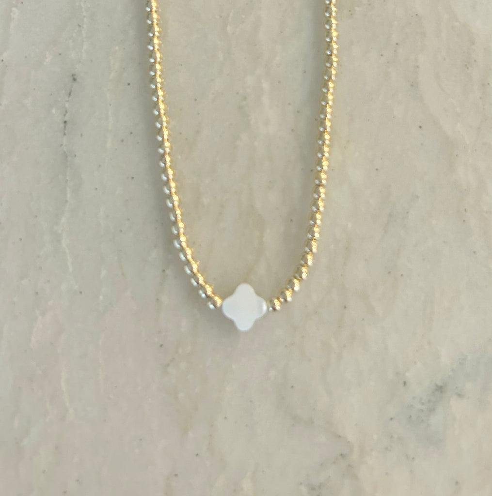 Clover Necklace by Pearly Girls, showcasing a delicate Mother of Pearl clover complemented by gold beads. This necklace elegantly blends the subtle iridescence of Mother of Pearl with the warm glow of gold beads, creating a graceful and charming accessory.