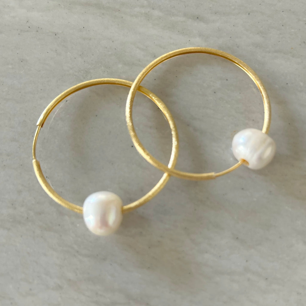 Gold Large Hoops with Freshwater Pearl by Pearly Girls, embodying contemporary elegance and timeless charm. These earrings pair the bold statement of large gold hoops with the classic beauty of a dangling freshwater pearl, creating a modern yet enduringly stylish accessory.