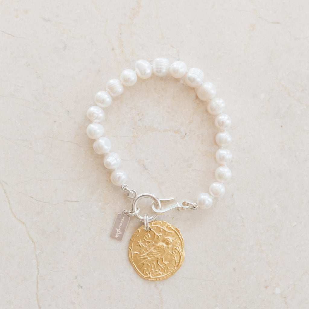 Callie Pearl Bracelet by Pearly Girls features nature-inspired elegance with a gold bird charm. This bracelet blends the classic beauty of pearls with the delicate intricacy of a gold bird charm, creating a piece that's both graceful and symbolic of freedom and serenity.