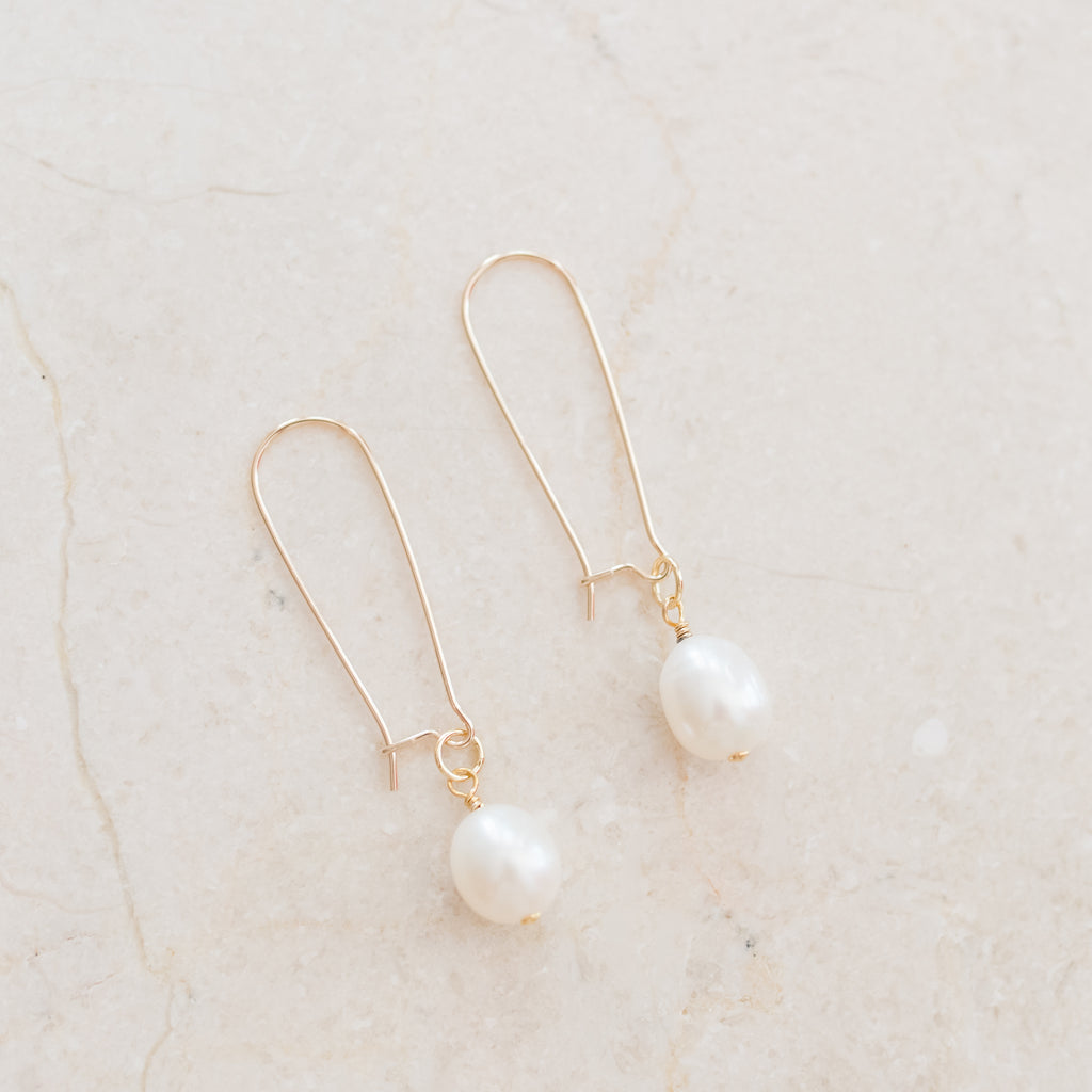 Gold-Filled Kidney Hook and Pearl Earrings by Pearly Girls, a fusion of modern elegance and classic pearls. These earrings feature sleek gold-filled kidney hooks, providing a contemporary edge, paired with the timeless beauty of dangling pearls for a sophisticated and chic look.