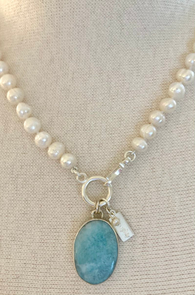 Laura Pearl Necklace by Pearly Girls, featuring ring pearls and a Larimar pendant. This necklace elegantly combines the textured beauty of ring pearls with the soothing blue hues of a Larimar pendant, creating a piece that's both visually striking and serene.