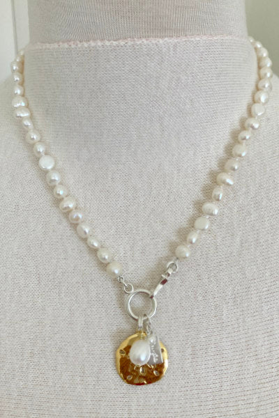 Boca Pearl Necklace by Pearly Girls, embodying seaside elegance with a sand dollar charm. This necklace artfully pairs classic pearls with a charming sand dollar pendant, capturing the serene beauty of the sea and adding a touch of coastal charm to the design.
