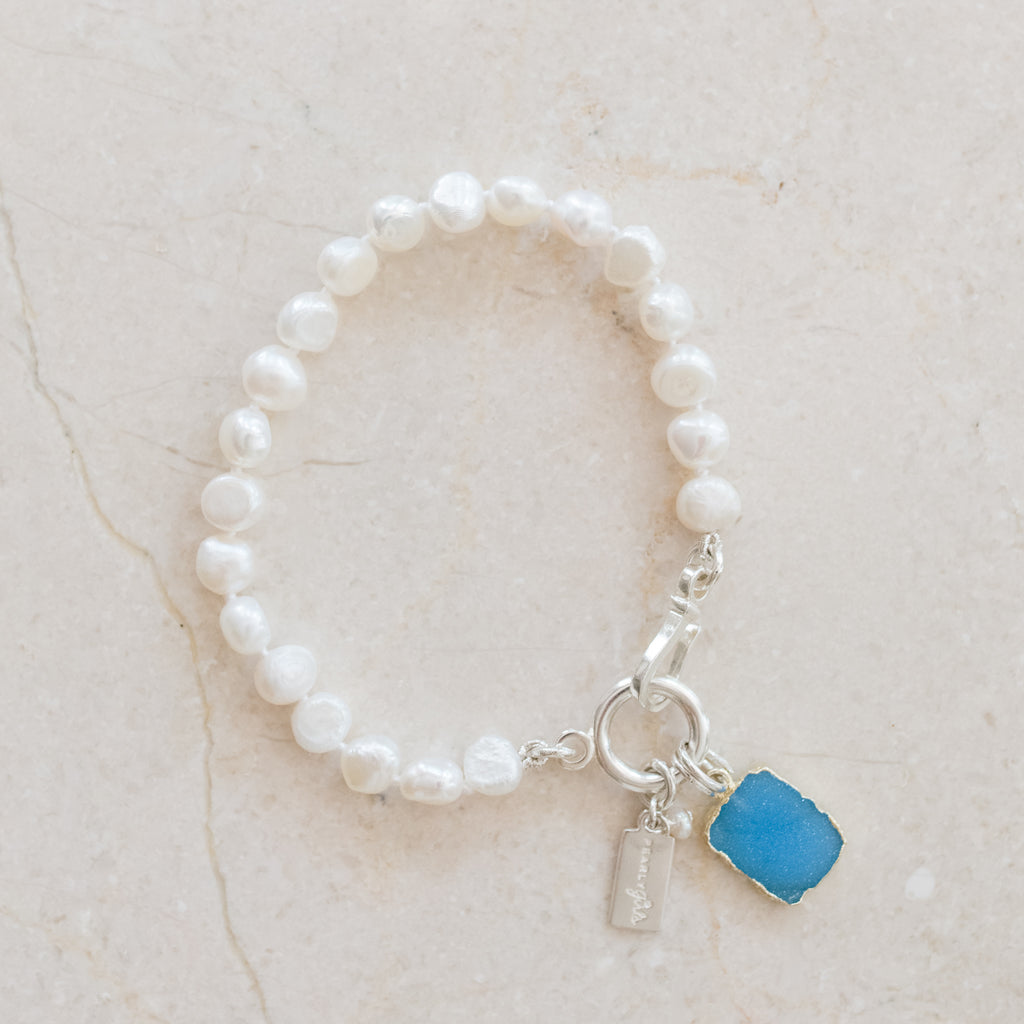 Whitney Blue Druzy & Freshwater Pearl Bracelet by Pearly Girls, embodying trendy elegance. This bracelet features the sparkling allure of a blue druzy stone paired with the classic beauty of freshwater pearls, creating a fashionable and elegant accessory that combines contemporary style with timeless charm.