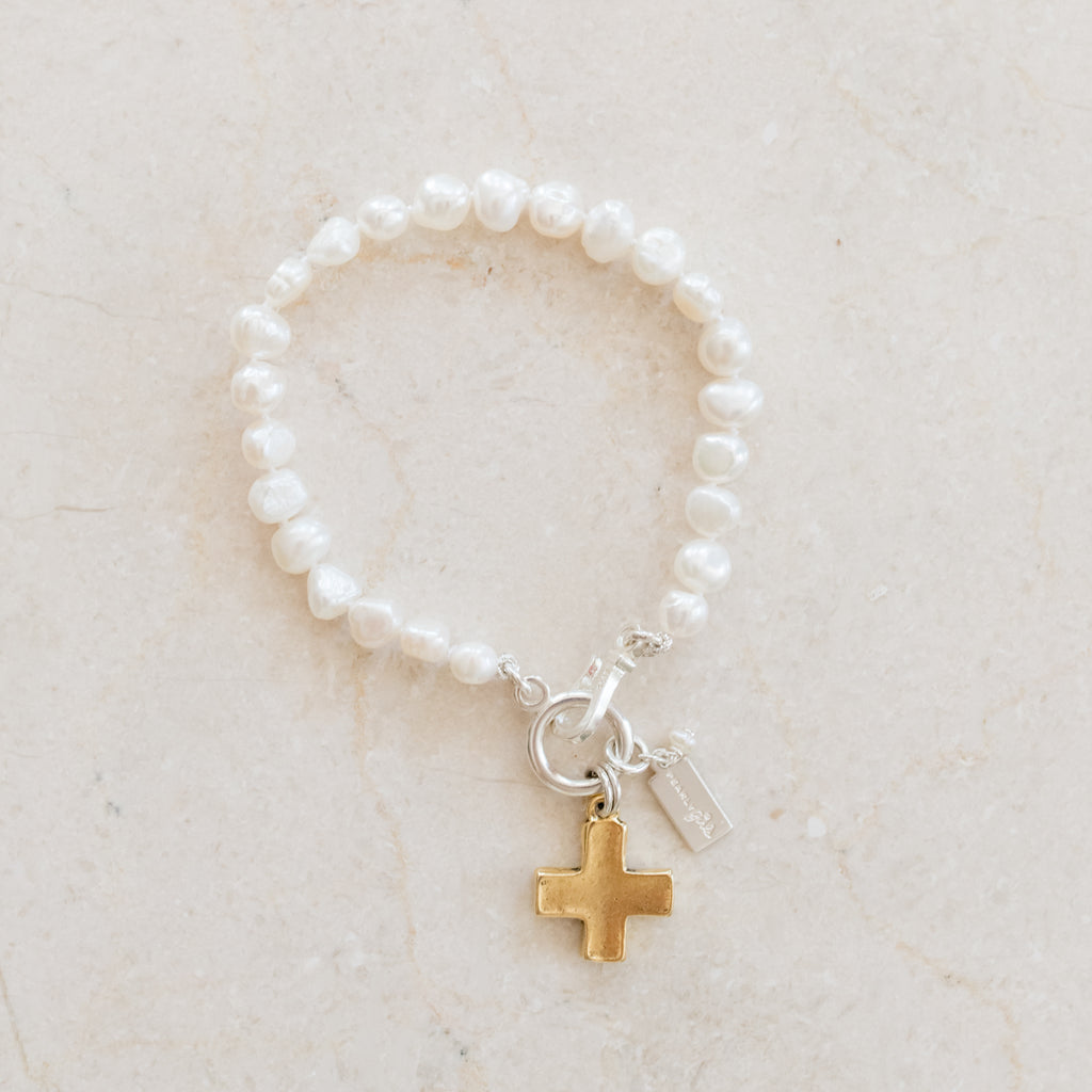 Reece Pearl Bracelet by Pearly Girls, featuring a single nugget freshwater pearl and a matte gold cross. This bracelet showcases the rustic charm of a nugget pearl paired with a matte gold cross, blending natural elegance with a symbol of faith in a simple, yet meaningful design.