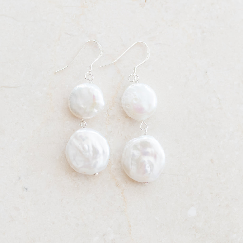 Double Coin Pearl Earrings by Pearly Girls, showcasing luminescent elegance with a double coin cascade. These earrings feature two layers of coin pearls, known for their unique, flat shape and lustrous sheen, creating a cascading effect that adds a touch of sophistication and modern flair.