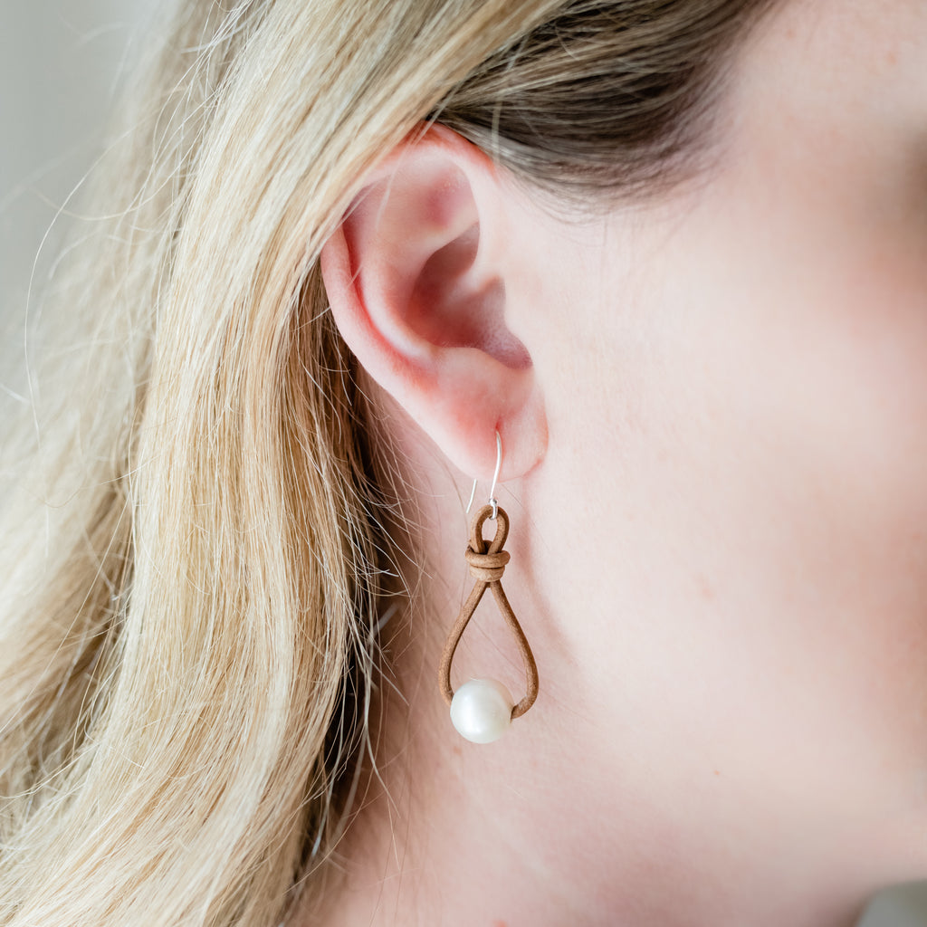 Leather and Pearl Earrings by Pearly Girls, featuring knotted leather and timeless pearls. These earrings creatively combine the rugged, organic feel of knotted leather with the classic elegance of pearls, creating a unique accessory that blends contrasting textures and styles.