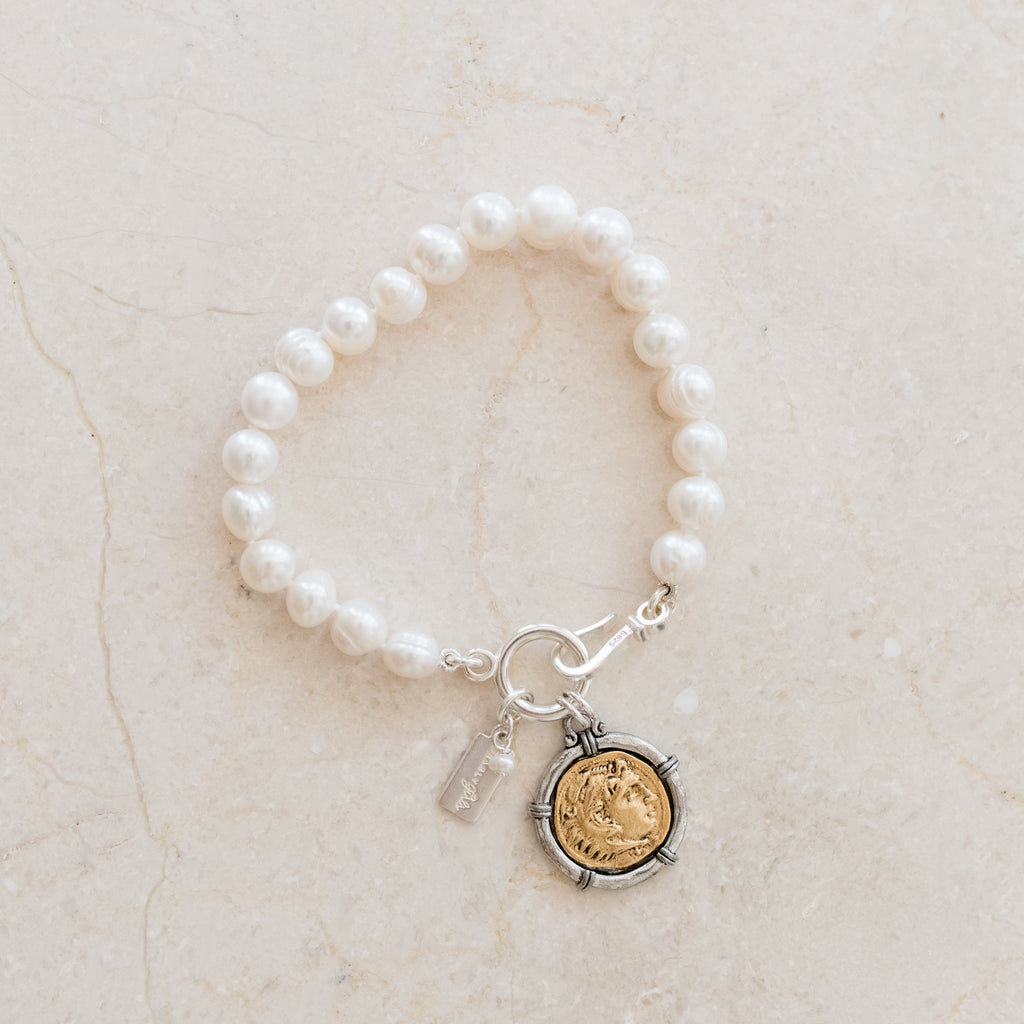 Nicole Pearl Bracelet by Pearly Girls, featuring a Greek coin charm and freshwater pearls. This bracelet artfully combines the historical elegance of a Greek coin charm with the timeless beauty of freshwater pearls, creating a piece that is both culturally rich and classically sophisticated.