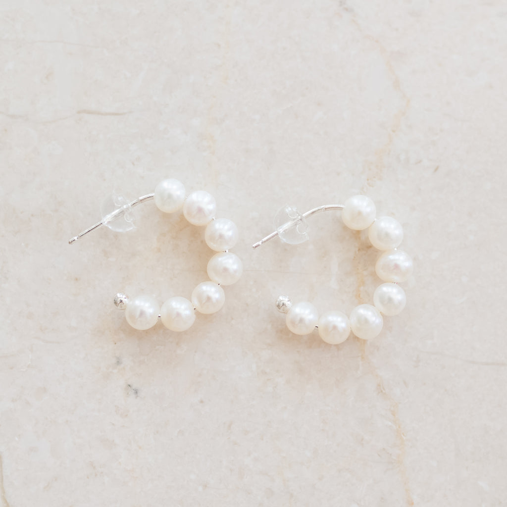 Half Hoop Pearl Earrings by Pearly Girls, a blend of modern elegance and timeless pearls. These earrings feature a contemporary half hoop design, paired with the classic allure of pearls, creating a sophisticated accessory that marries traditional beauty with a modern twist.