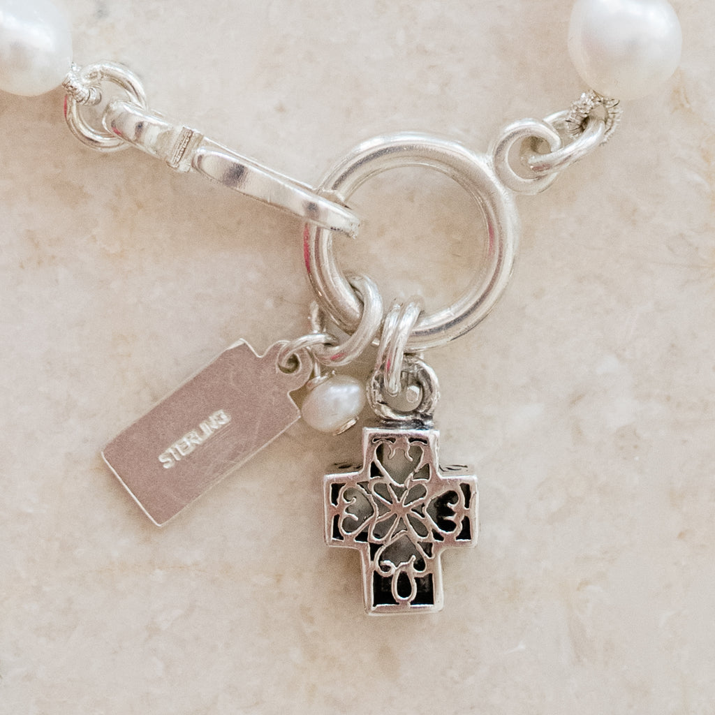 Faith Pearl Bracelet by Pearly Girls, featuring freshwater pearls and a Mother of Pearl cross. This bracelet pairs the timeless elegance of pearls with the serene beauty of a Mother of Pearl cross, creating a spiritually inspired and graceful accessory.