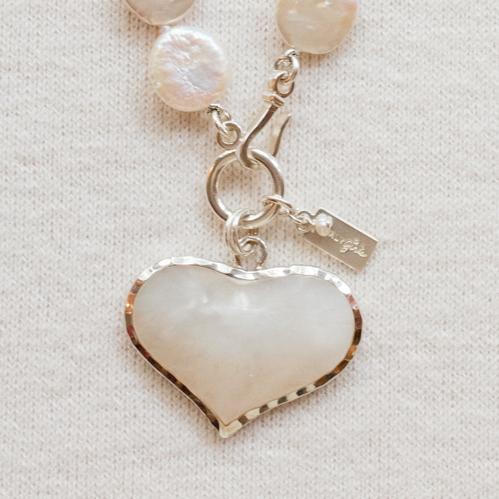 Louise Pearl Necklace by Pearly Girls, featuring a Mother of Pearl heart pendant. This necklace gracefully combines the lustrous elegance of pearls with a beautifully crafted Mother of Pearl heart pendant, symbolizing love and tenderness in a sophisticated design.