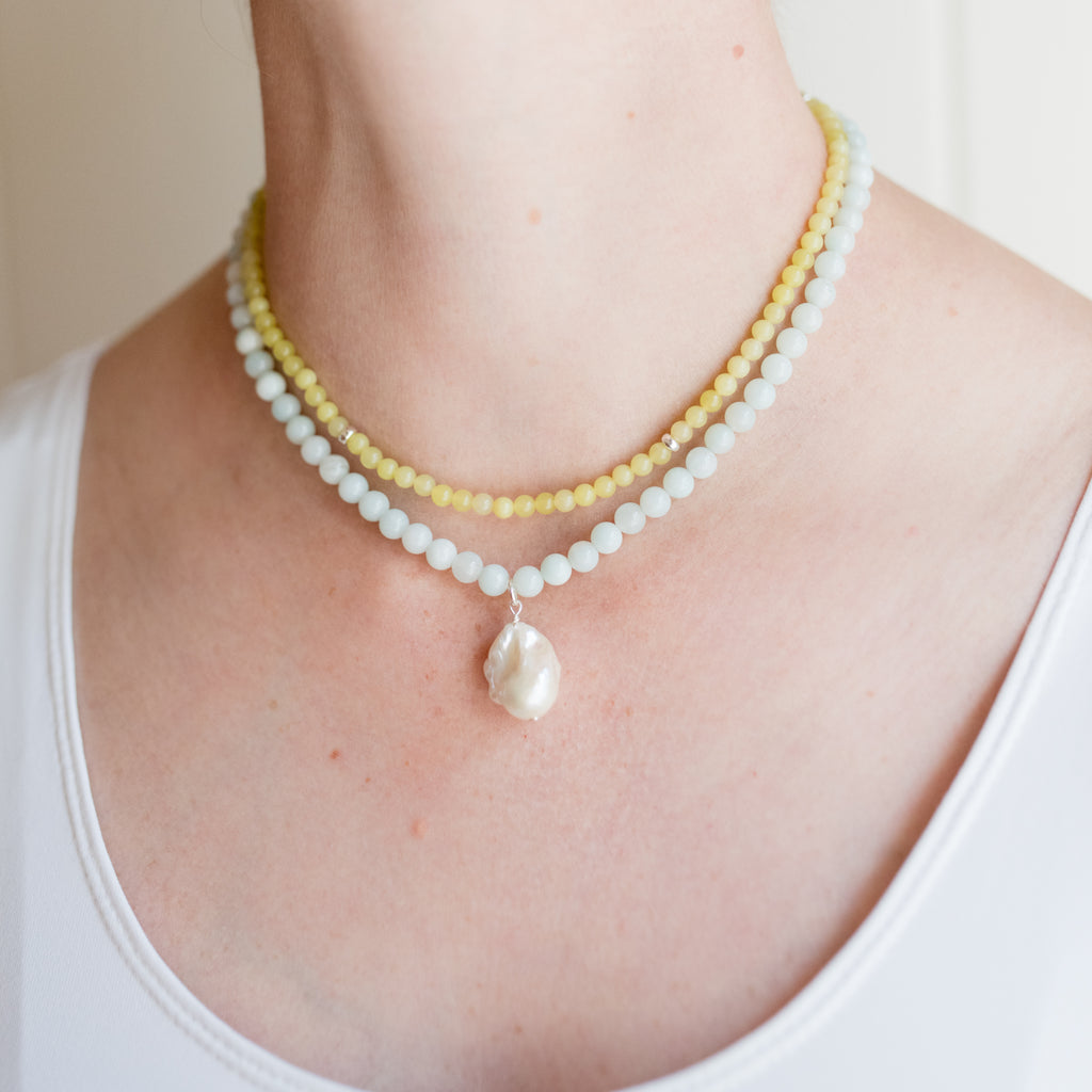 Heather Pearl Necklace by Pearly Girls, featuring amazonite and a fireball pendant. This necklace artfully combines the serene blue-green hues of amazonite with a striking fireball pendant, creating a piece that beautifully merges the tranquility of gemstones with the boldness of the pendant.