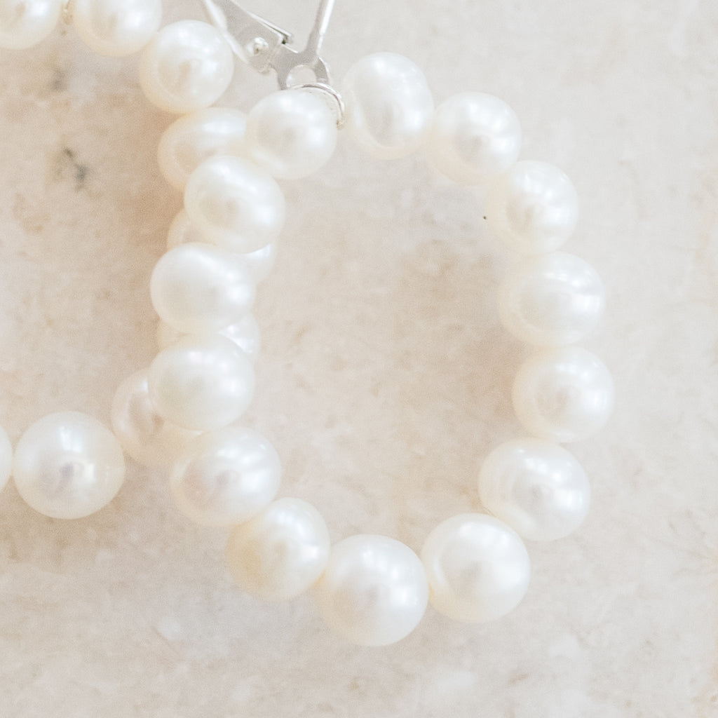 Oval Pearl Hoop Earrings by Pearly Girls, showcasing freshwater pearl elegance. These earrings feature a modern oval hoop design, adorned with lustrous freshwater pearls, creating a piece that combines contemporary style with the classic beauty of pearls.
