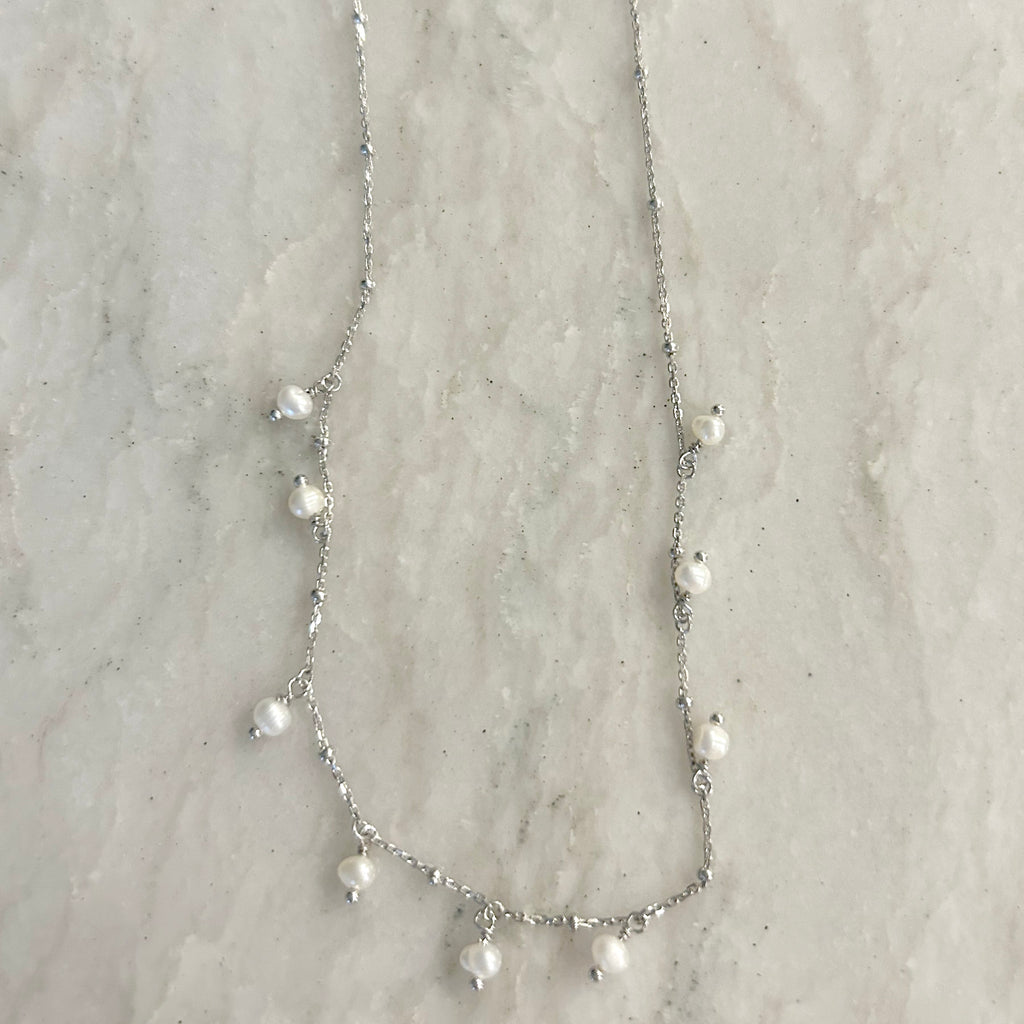 Jill Dainty Pearl Necklace by Pearly Girls, featuring delicate freshwater pearls and an adjustable silver chain. This necklace elegantly strings together small, lustrous pearls on a fine silver chain, offering a subtle and graceful piece that can be adjusted for a perfect fit.