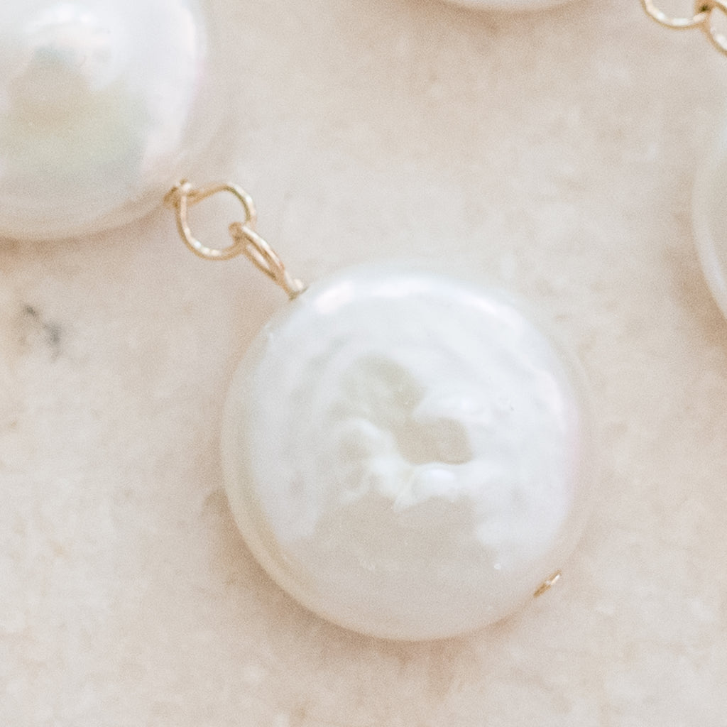 Triple Coin Pearl Earrings by Pearly Girls, a set of freshwater pearl earrings. These earrings feature three layers of coin pearls, known for their unique, flat shape, offering a modern twist on classic pearl earrings with a stacked, dimensional design that adds elegance and interest.