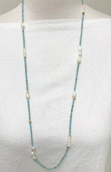 Jess Turquoise and Pearl Necklace by Pearly Girls, a long artisan elegance turquoise necklace with gold accents. This necklace artfully blends vibrant turquoise beads with classic pearls, highlighted by touches of gold, creating a piece that exudes both the richness of artisan craftsmanship and the timeless beauty of mixed materials.