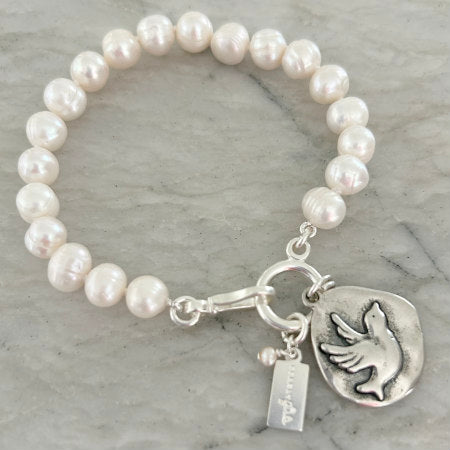 Hope Pearl Bracelet by Pearly Girls, featuring ring pearls and a sterling silver bird charm. This bracelet combines the distinctive texture of ring pearls with a delicate sterling silver bird charm, symbolizing freedom and aspiration, creating an accessory that's both elegant and meaningful.