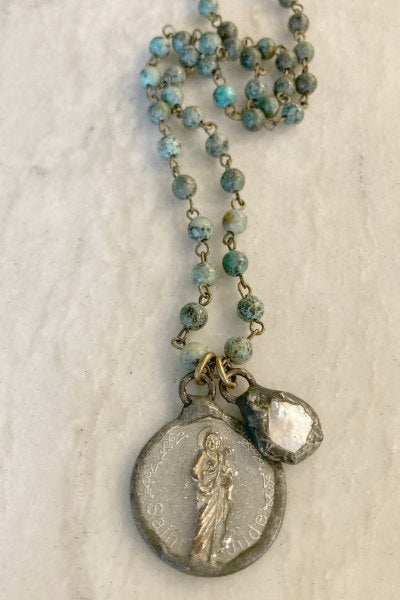 Zoey African Turquoise & St. Jude Pendant Necklace by Pearly Girls, a symbol of inspirational elegance. This necklace features the rich, earthy tones of African turquoise beads paired with a St. Jude pendant, creating a piece that combines spiritual significance with the natural beauty of gemstones.