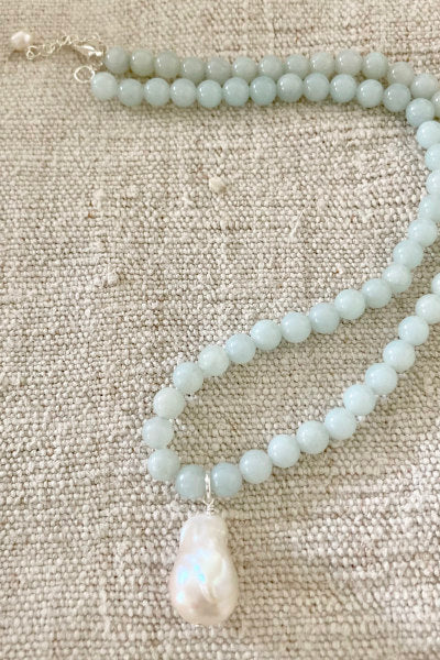Heather Pearl Necklace by Pearly Girls, featuring amazonite and a fireball pendant. This necklace artfully combines the serene blue-green hues of amazonite with a striking fireball pendant, creating a piece that beautifully merges the tranquility of gemstones with the boldness of the pendant.