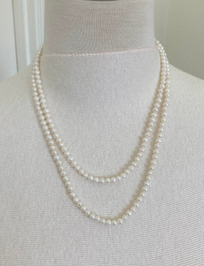 Classic Near Round Pearl Necklace by Pearly Girls, a 40-inch white pearl strand. This necklace showcases a continuous line of near-round pearls, offering a traditional and elegant look with its long length and the timeless allure of classic white pearls.
