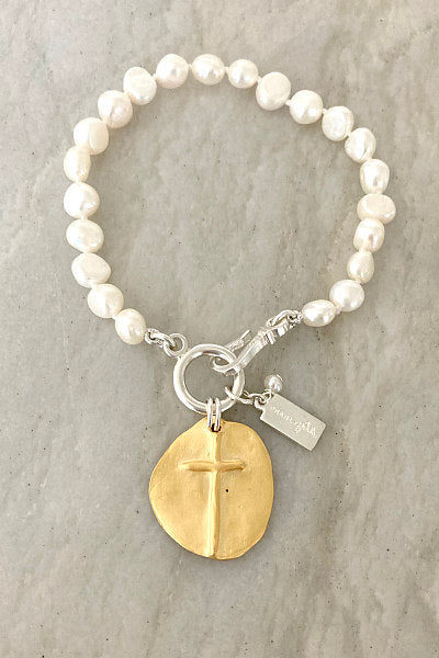 Sophie Gold Pearl Bracelet by Pearly Girls, featuring a matte gold cross and heart. This bracelet elegantly pairs the luster of pearls with a matte gold cross and heart, blending spiritual symbolism with a touch of romantic charm in a design that's both graceful and meaningful.