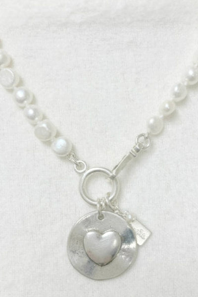 Cupid Pearl Necklace by Pearly Girls features freshwater nugget pearls and a sterling silver LOVE disc. This necklace beautifully blends the natural, irregular shapes of nugget pearls with the symbolic LOVE disc in sterling silver, creating a piece that's both romantic and elegantly casual.