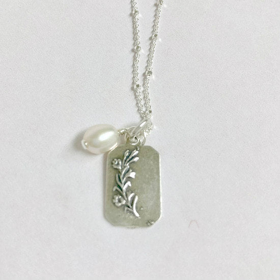 Mary Pearl Necklace by Pearly Girls, featuring a sterling silver Saint tag and freshwater pearl. This necklace combines the spiritual symbolism of a Saint tag in sterling silver with the timeless elegance of a freshwater pearl, creating a piece that is both meaningful and classically beautiful.