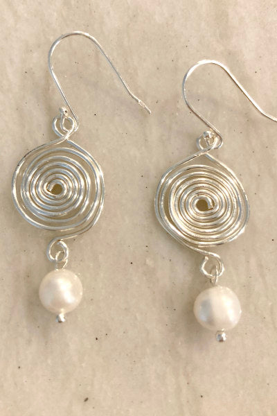 Silver Spiral Earrings with Pearl Drop by Pearly Girls, embodying whimsical elegance. These earrings feature a playful silver spiral design, gracefully leading to a lustrous pearl drop, creating a unique and charming accessory that combines a touch of whimsy with classic pearl sophistication.